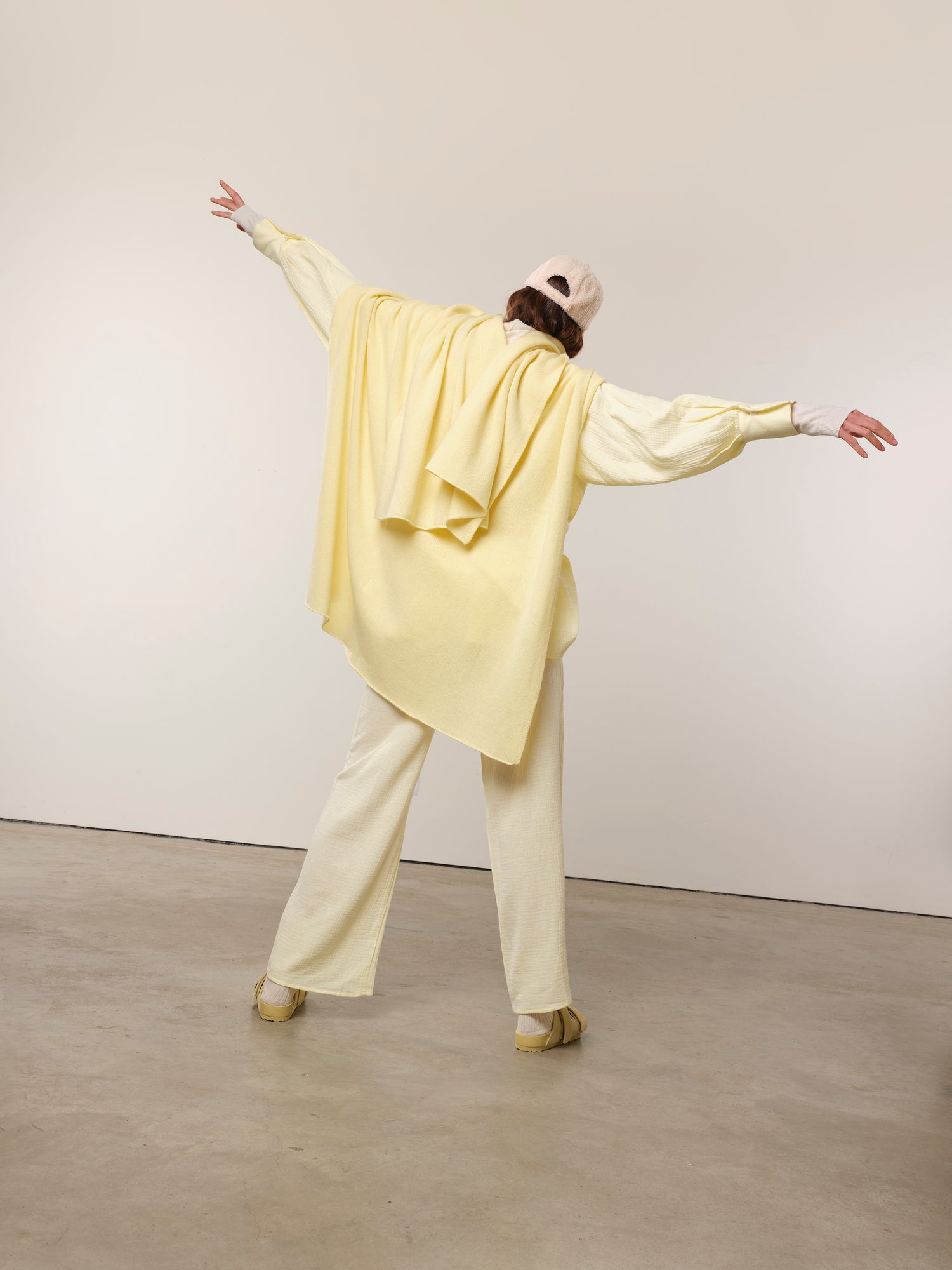 Lemon coloured Soft cashmere gift shawl, designed to offer warmth and comfort during medical journeys worn by a model in lemon coloured pyjamas and baseball hat. Perfect for layering over a patient gown or staying cozy at home. Gentle on the skin with uplifting colours that brighten any day, providing a comforting and thoughtful gift.