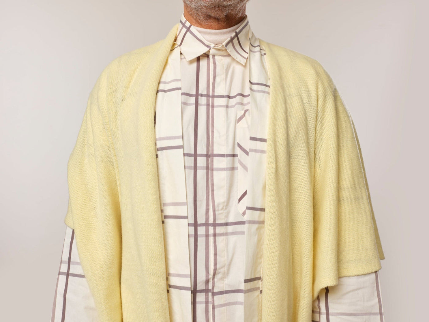 Lemon coloured Soft cashmere gift shawl, designed to offer warmth and comfort during medical journeys. Worn on male model over a pair of check print pyjamas. Perfect for layering over a patient gown or staying cozy at home. Gentle on the skin with uplifting colours that brighten any day, providing a comforting and thoughtful gift.