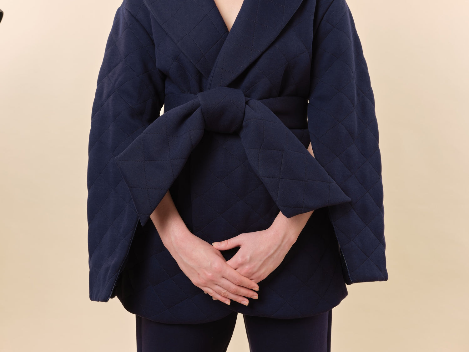Model wearing luxury chemotherapy clothing featuring a navy silk-lined wrap jacket with zipper arm access and quilted design for comfort. Made from breathable, skin-friendly quilted jersey fabric for warmth and convenience during treatment sessions, with an optional matching Cashmere Therapy Shawl for added luxury.