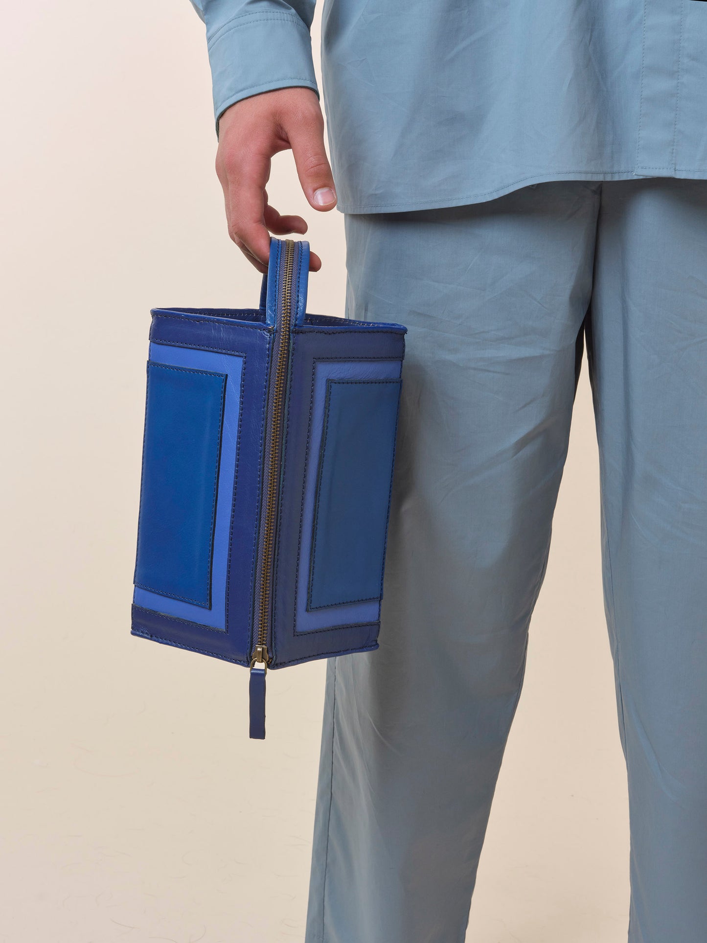 Person holding a blue leather medication travel bag