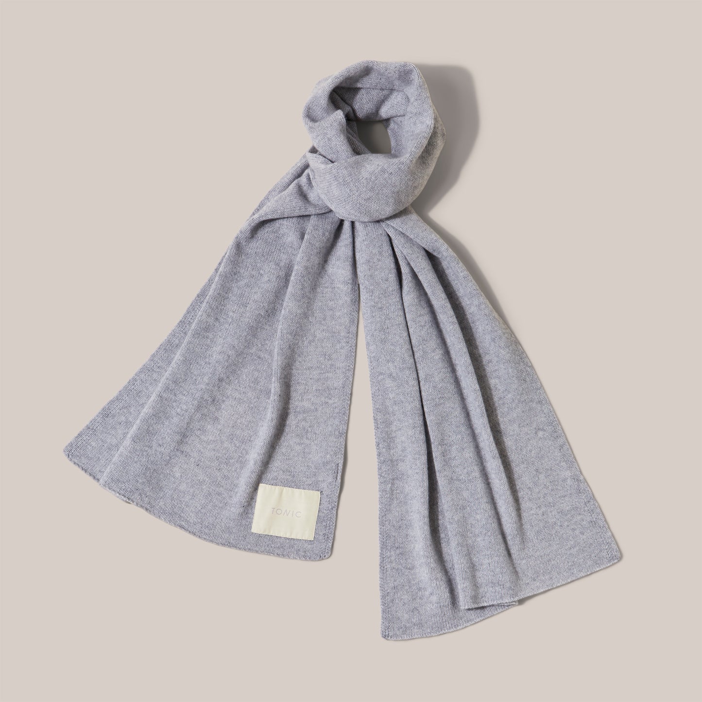 Wide grey cashmere scarf arranged as if worn and showing label detail.