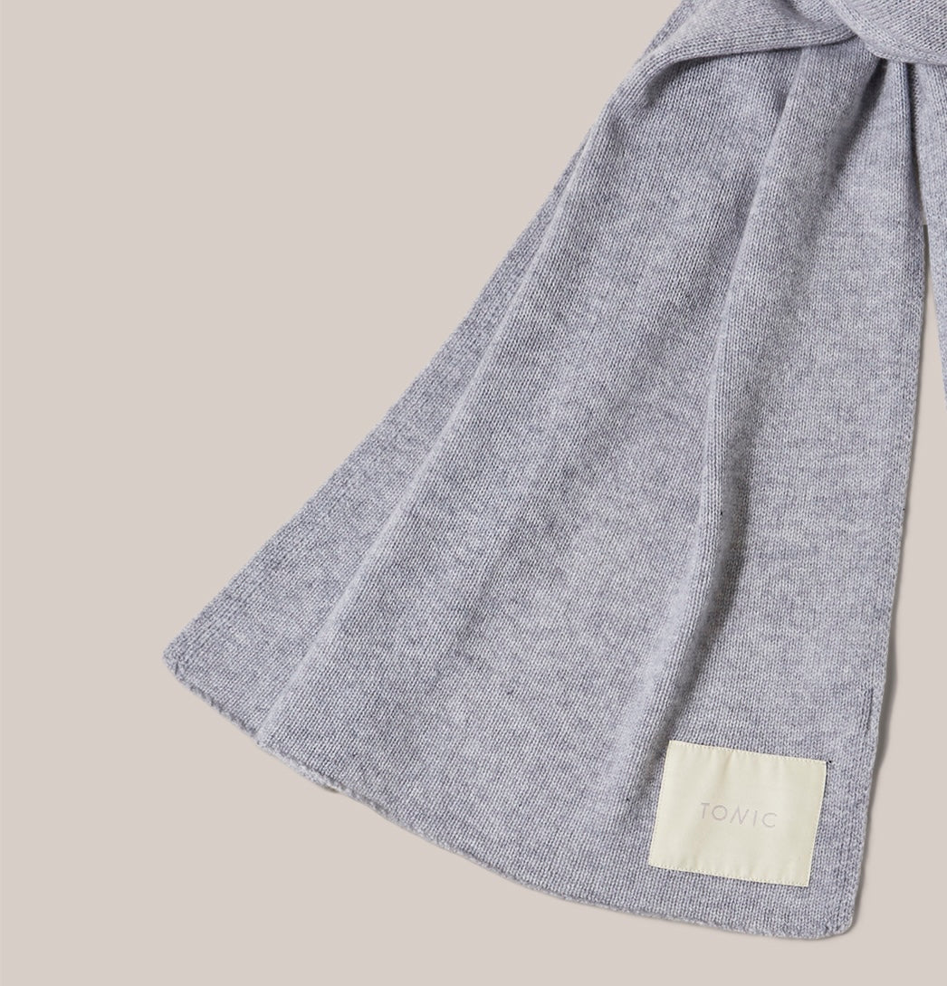 Zoomed in detail of scarf. Wide grey cashmere scarf arranged as if worn and showing label detail.