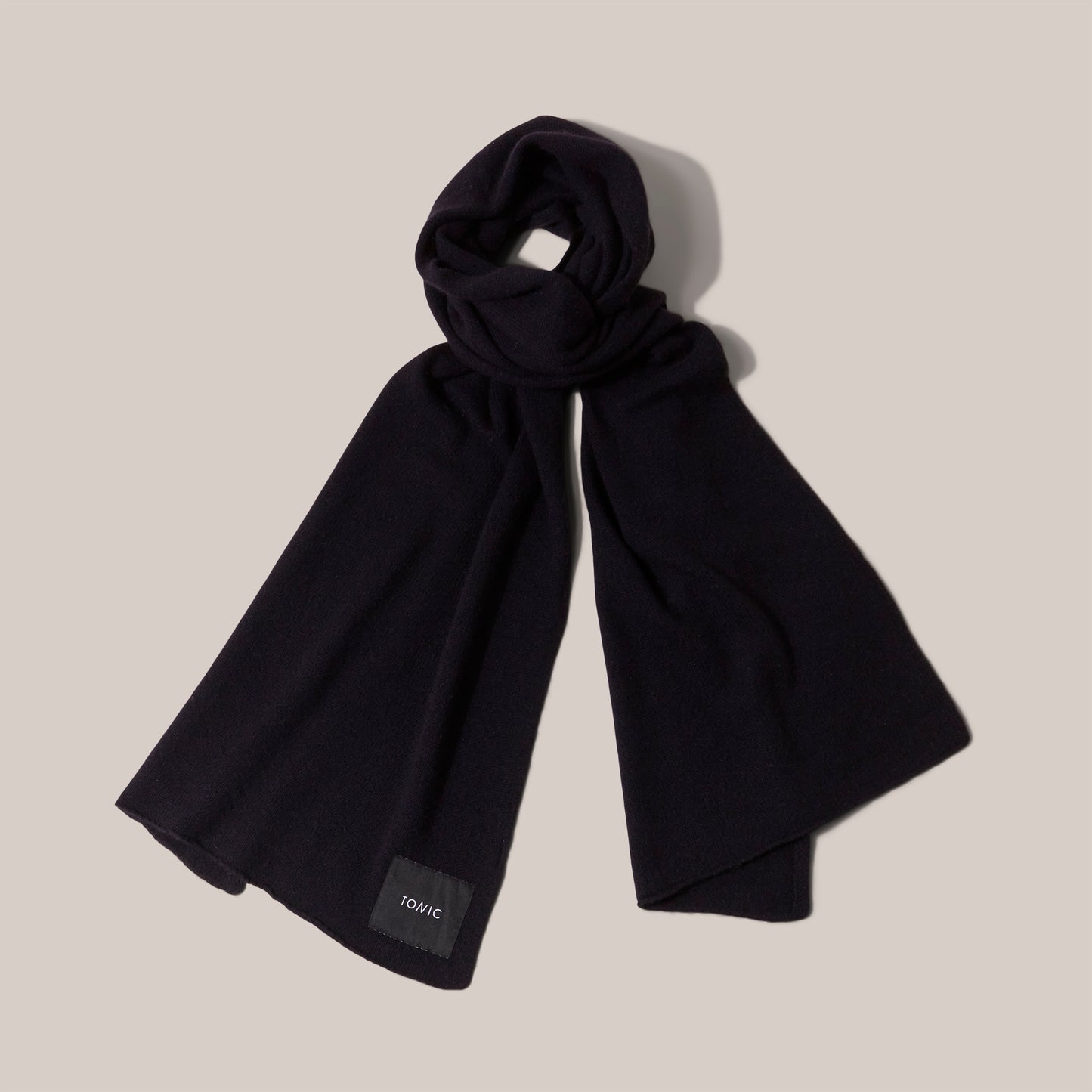 Wide navy cashmere scarf arranged as if worn and showing label detail.