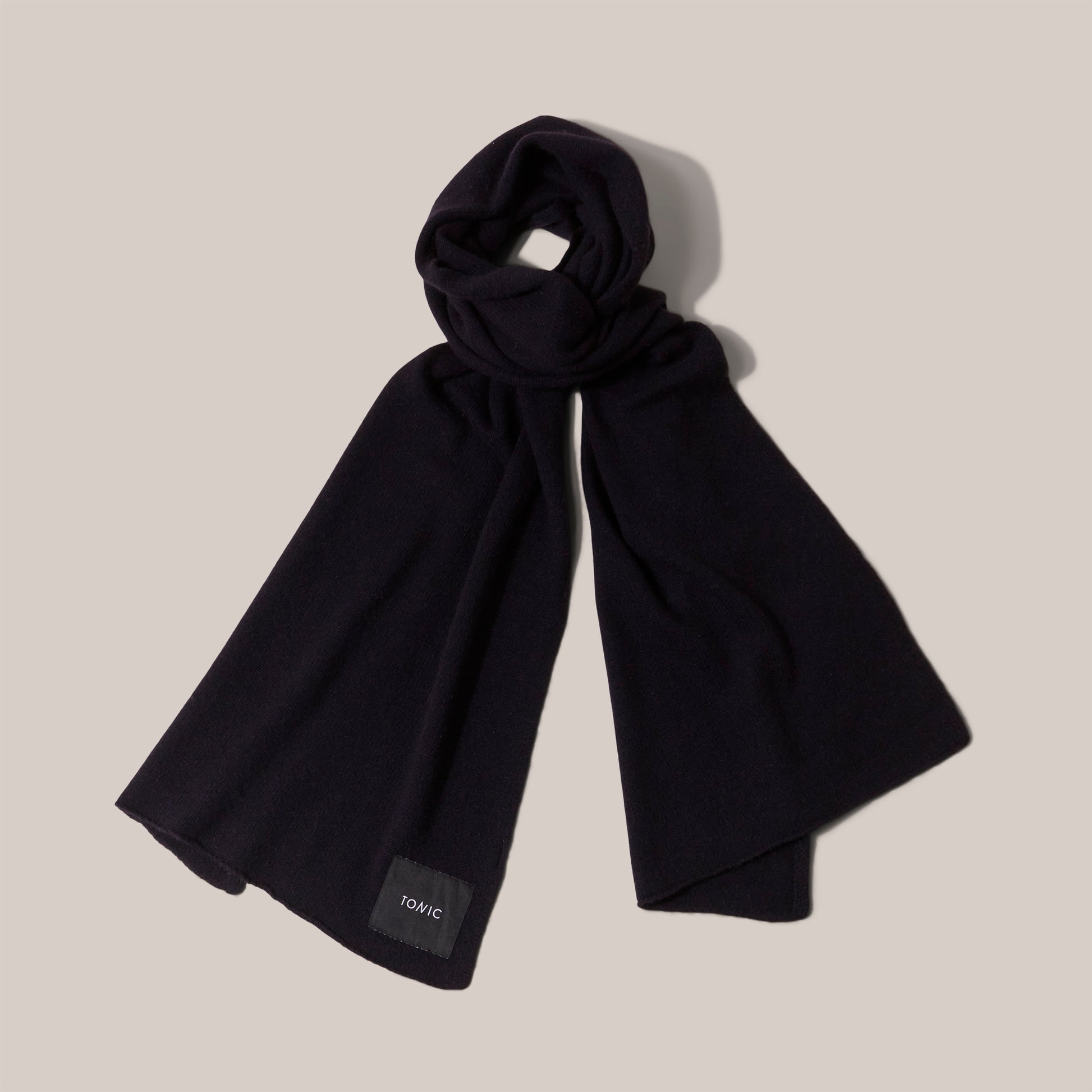 Wide navy cashmere scarf arranged as if worn and showing label detail.
