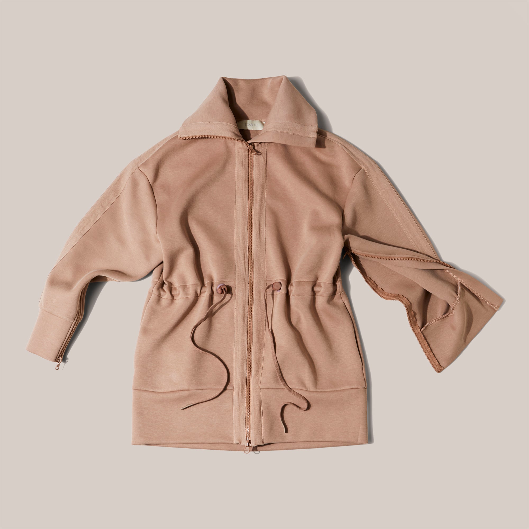 Product shot of chemotherapy treatment jacket in caramel with zip access on the arms and zip through detail to give access for treatment lines. The product is a luxury one.