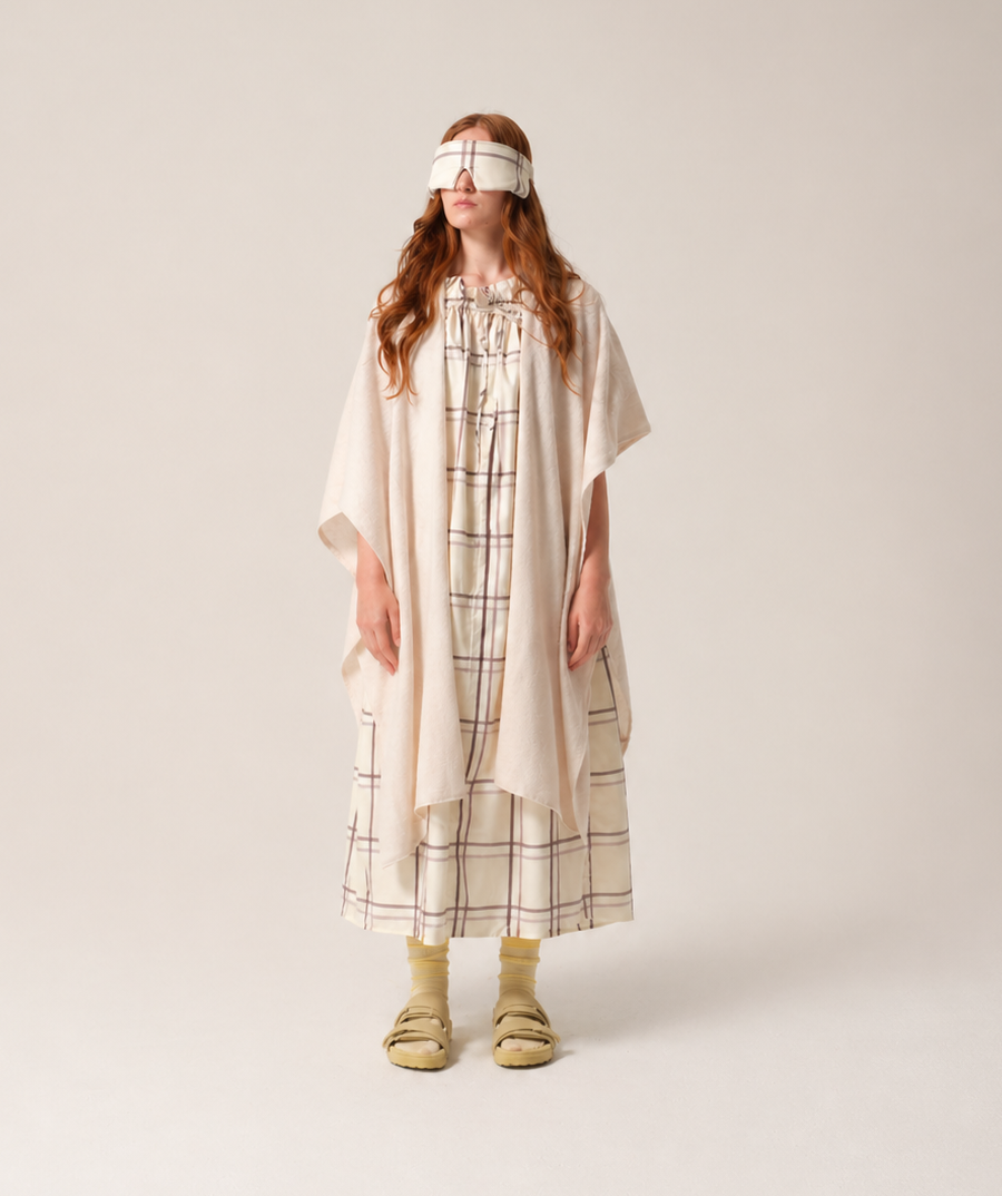 Woman Person wearing a checkered patient hospital gown and a white headband on a plain background and cashmere recuperation shawl from TONIC London patient wear